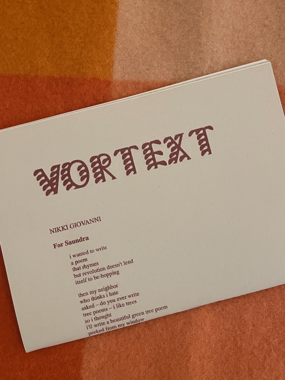 A photograph of the second issue of VORTEXT, folded in half, with the title poem 'For Saundra' by Nikki Giovanni partly visible.
